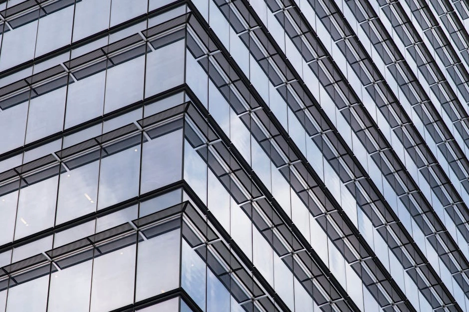 Moderní kancelářská budova se skleněnou fasádou odrážející oblohu